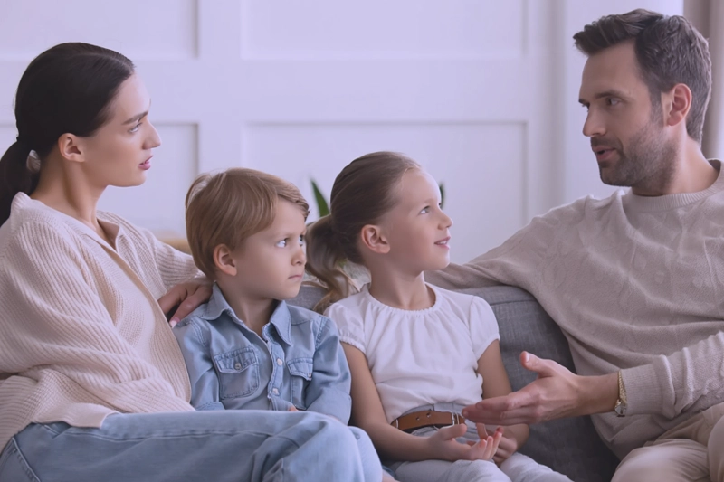 Семья сидит на диване и разговаривает